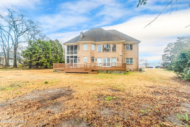 rear view of property with a yard, a sunroom, cooling unit, and a wooden deck