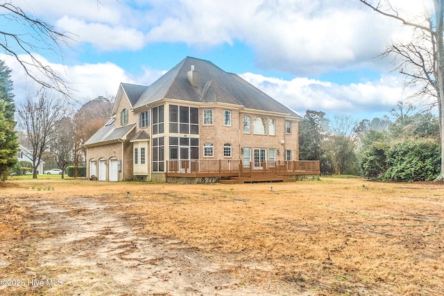 back of property featuring a sunroom, a garage, and a deck