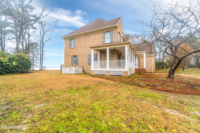 view of side of home featuring covered porch and a yard