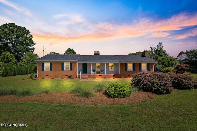 ranch-style house with covered porch and a lawn