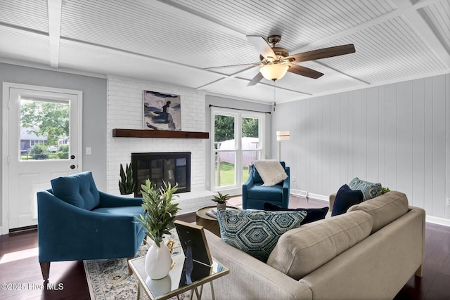 living room featuring ceiling fan, a healthy amount of sunlight, dark hardwood / wood-style flooring, and a fireplace