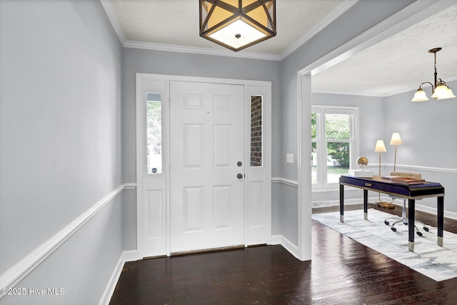 foyer entrance featuring dark hardwood / wood-style flooring, a chandelier, a textured ceiling, and ornamental molding