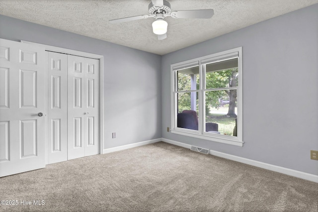 unfurnished bedroom with ceiling fan, a closet, carpet floors, and a textured ceiling