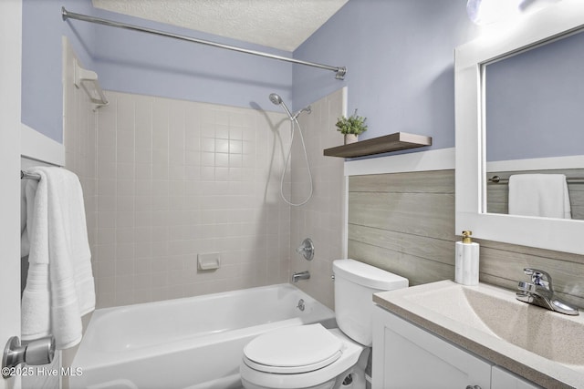 full bathroom with tiled shower / bath combo, toilet, a textured ceiling, and vanity