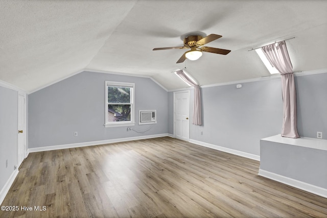 bonus room featuring ceiling fan, light hardwood / wood-style flooring, a wall mounted AC, a textured ceiling, and vaulted ceiling