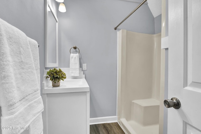 bathroom featuring hardwood / wood-style flooring, vanity, and walk in shower