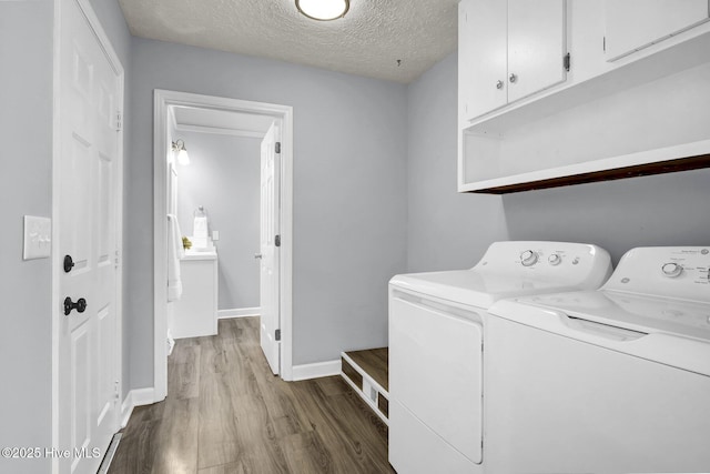 clothes washing area with cabinets, a textured ceiling, light hardwood / wood-style floors, and washer and dryer