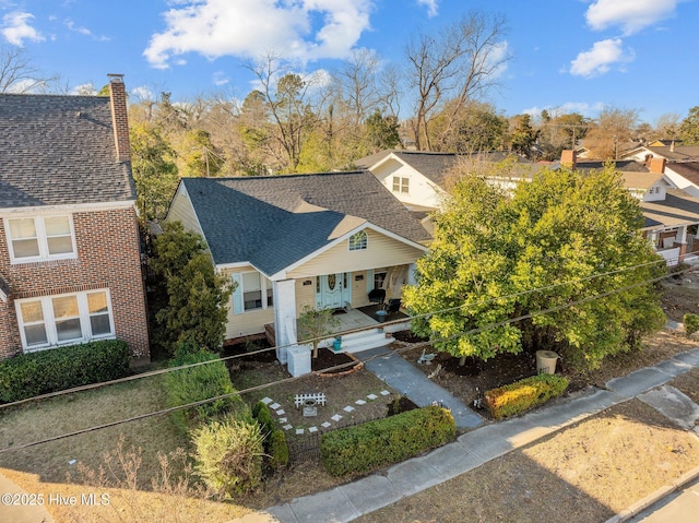 view of front of house with a chimney, covered porch, and a shingled roof