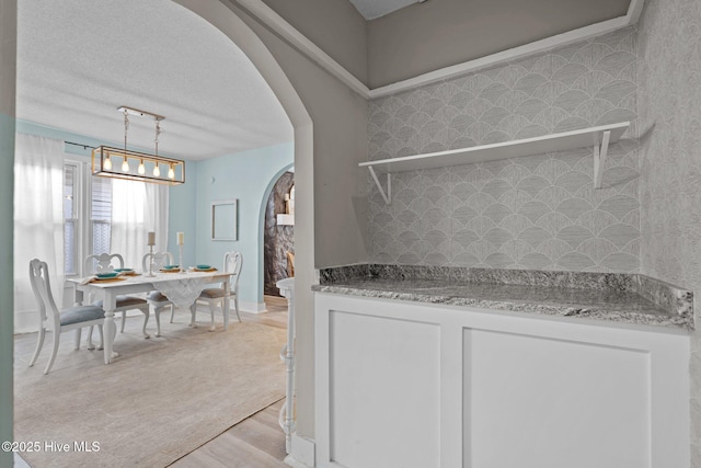 kitchen featuring pendant lighting, light hardwood / wood-style floors, light stone counters, and white cabinets