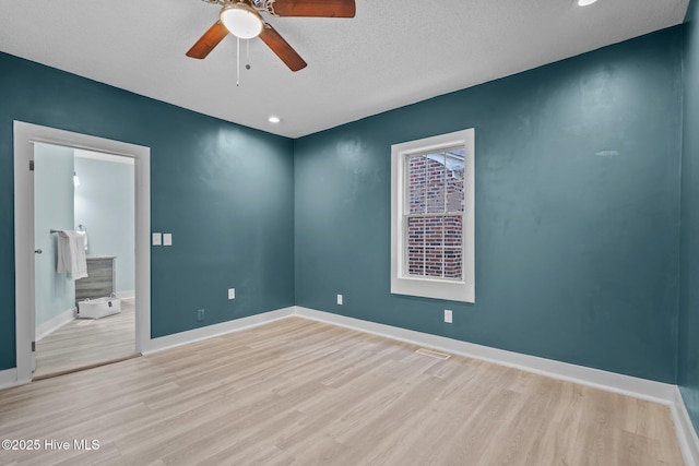 empty room with ceiling fan, light hardwood / wood-style floors, and a textured ceiling