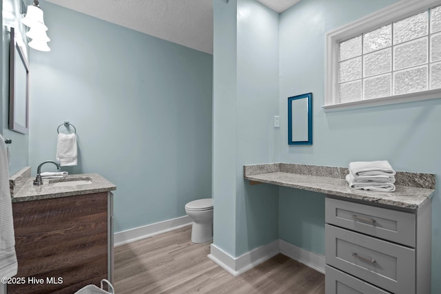 bathroom with hardwood / wood-style flooring, vanity, a textured ceiling, and toilet