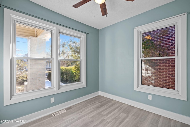 spare room with ceiling fan, a textured ceiling, and light hardwood / wood-style floors