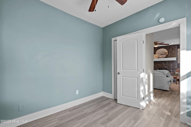 bedroom featuring a textured ceiling, a fireplace, light hardwood / wood-style floors, and ceiling fan