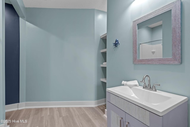 bathroom with hardwood / wood-style floors, vanity, walk in shower, a textured ceiling, and built in shelves