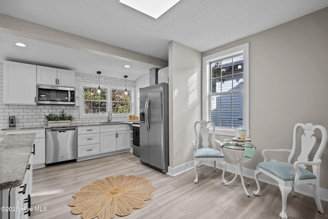 kitchen featuring white cabinetry, a textured ceiling, appliances with stainless steel finishes, pendant lighting, and decorative backsplash