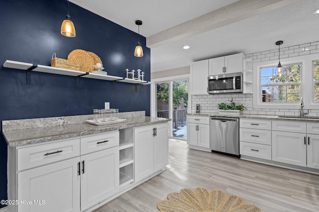 kitchen with pendant lighting, beamed ceiling, white cabinetry, sink, and stainless steel appliances