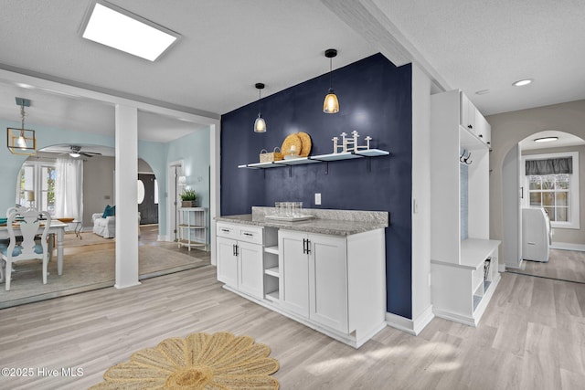 kitchen featuring white cabinetry, light stone counters, light hardwood / wood-style floors, and a textured ceiling