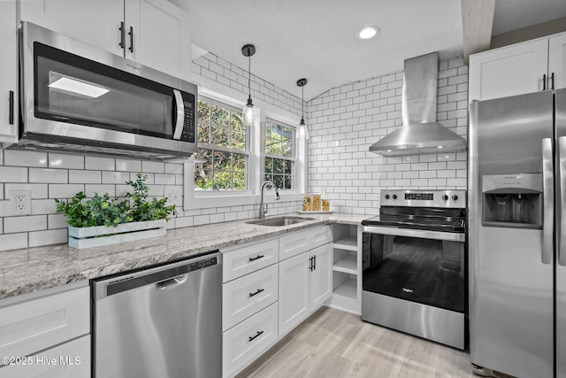 kitchen with sink, white cabinetry, a textured ceiling, appliances with stainless steel finishes, and wall chimney range hood