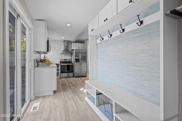 mudroom with light hardwood / wood-style floors and a textured ceiling