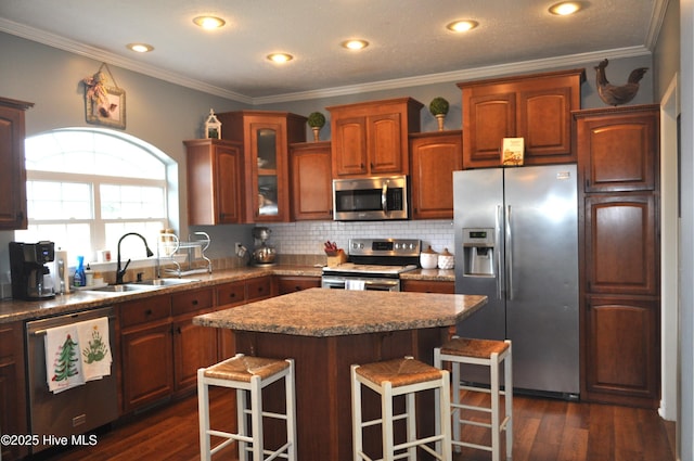 kitchen featuring sink, appliances with stainless steel finishes, a kitchen island, dark hardwood / wood-style flooring, and a breakfast bar area