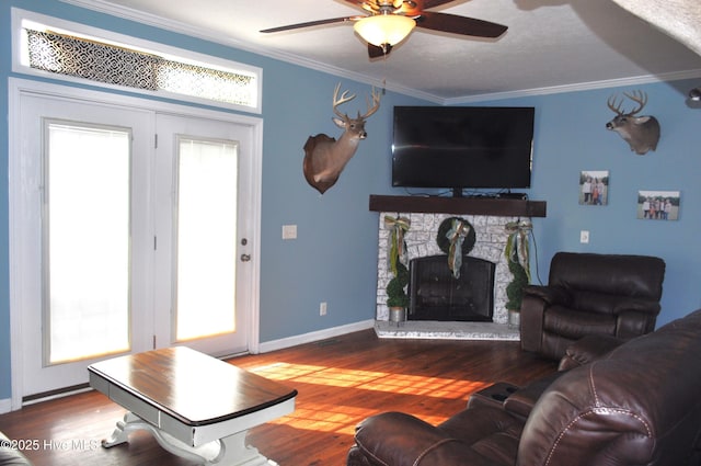 living room featuring ceiling fan, a fireplace, wood-type flooring, and ornamental molding