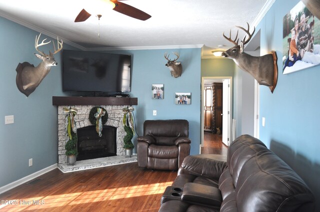 living room with hardwood / wood-style flooring, ceiling fan, a fireplace, and crown molding