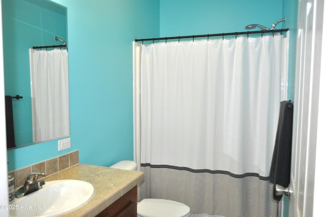 bathroom featuring a shower with shower curtain, vanity, and toilet