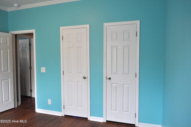 unfurnished bedroom with ornamental molding and dark wood-type flooring