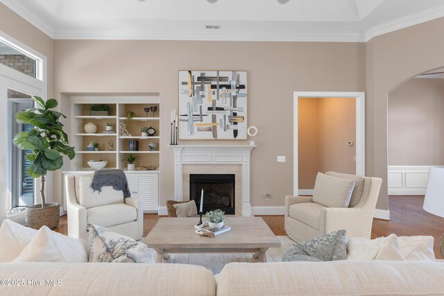 living area featuring visible vents, arched walkways, ornamental molding, wood finished floors, and a fireplace