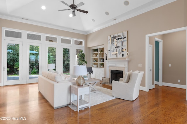 living area with crown molding, a fireplace, baseboards, and wood finished floors