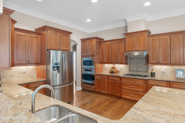 kitchen featuring appliances with stainless steel finishes, a sink, under cabinet range hood, and light stone countertops