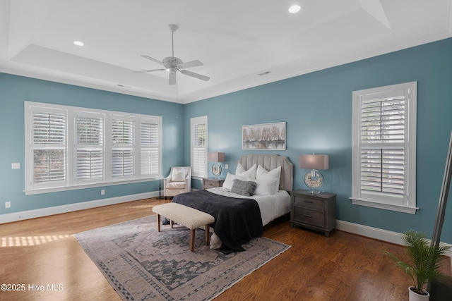 bedroom featuring a tray ceiling, multiple windows, and baseboards