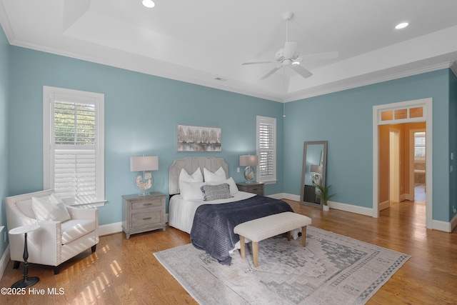 bedroom with recessed lighting, a raised ceiling, baseboards, and wood finished floors