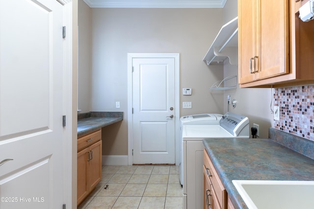 washroom with cabinet space, crown molding, washer and dryer, a sink, and light tile patterned flooring