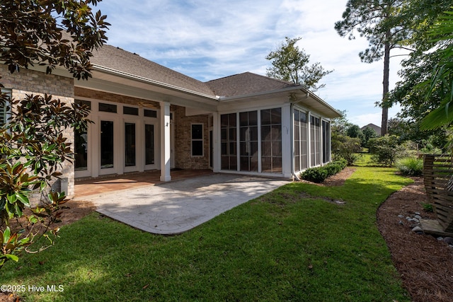 back of house featuring a shingled roof, a patio area, a lawn, and brick siding