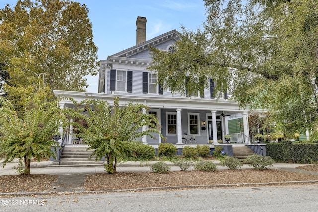 greek revival inspired property featuring a porch and a chimney