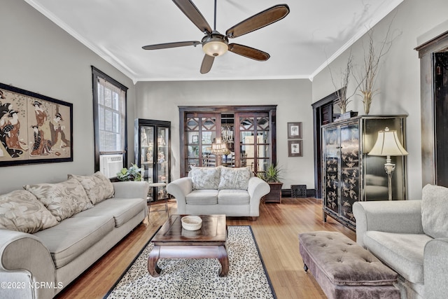 living room with ornamental molding, light wood-type flooring, a ceiling fan, and baseboards