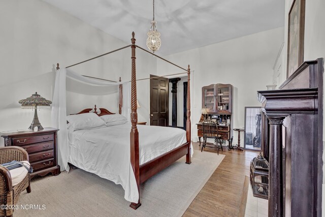 bedroom with crown molding, a fireplace, and light hardwood / wood-style flooring