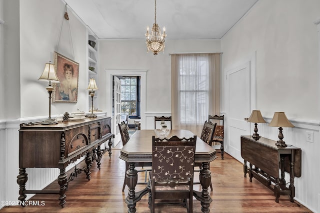 dining space featuring a chandelier, a wainscoted wall, and wood finished floors