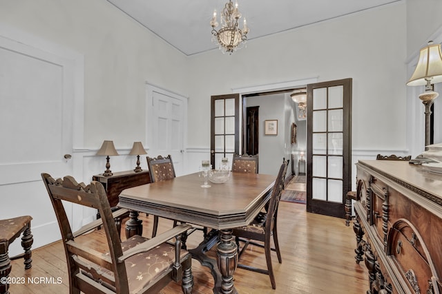 dining area featuring light wood-style flooring, a chandelier, and french doors