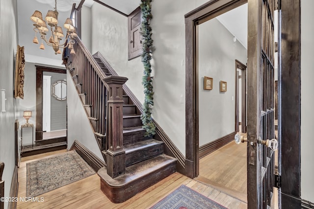 entryway featuring a notable chandelier, stairway, baseboards, and wood finished floors