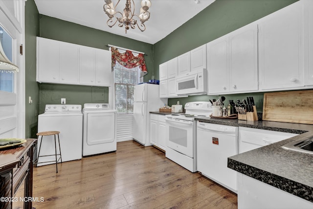 kitchen with white appliances, washer and dryer, white cabinets, dark countertops, and decorative light fixtures