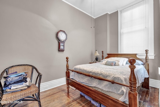 bedroom featuring ornamental molding, baseboards, and wood finished floors