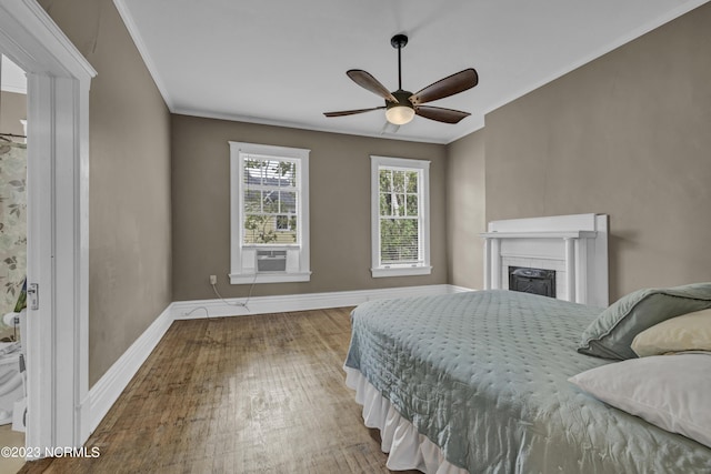 bedroom with a fireplace, crown molding, wood finished floors, cooling unit, and baseboards