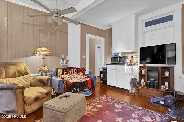 living room with crown molding, beam ceiling, dark hardwood / wood-style floors, and ceiling fan