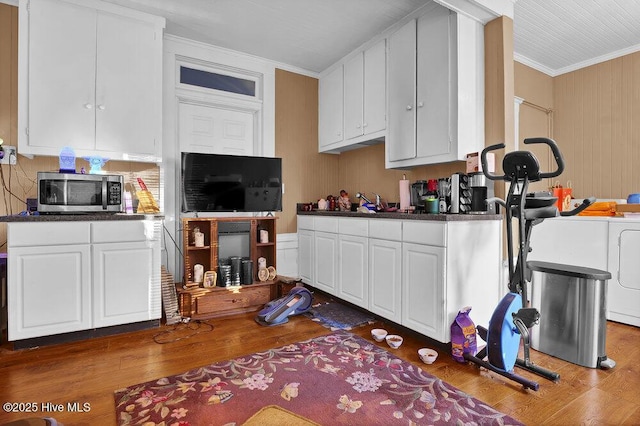 kitchen with dark hardwood / wood-style flooring, ornamental molding, white cabinets, and washer and clothes dryer