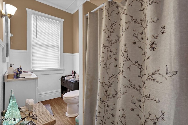 full bath with wainscoting, toilet, wood finished floors, crown molding, and vanity