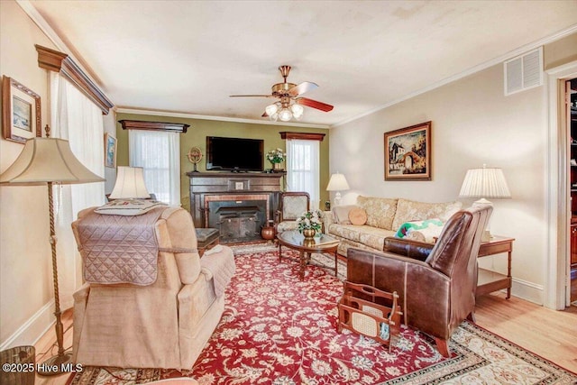 living room with light wood-type flooring, ceiling fan, and ornamental molding