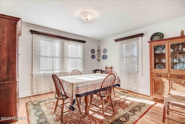 dining room with ornamental molding, a textured ceiling, and light hardwood / wood-style flooring