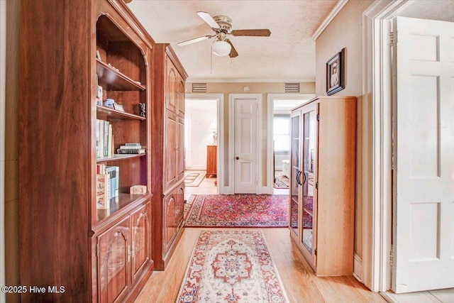 corridor with a textured ceiling and light wood-type flooring